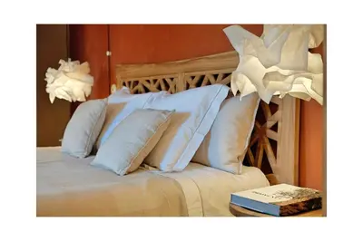 a bed with white pillows and a book on a table at Les Jardins de Sitaara in Cucuron