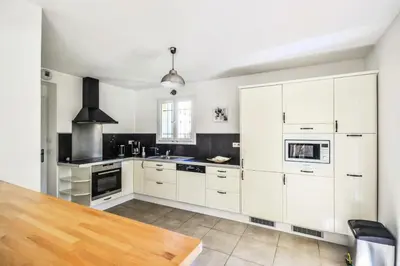 a kitchen with white cabinets and a wooden table at Les Mas et Villas de Pont Royal en Provence - maeva Home - Villa 5 Pièces 8 Personnes avec piscine privée et vue sur le golf - Exclusive - super Home MAE-6074 in Mallemort