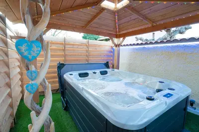 a hot tub in a gazebo with a wooden roof at Lovina chambre de charme avec jacuzzi in Velaux