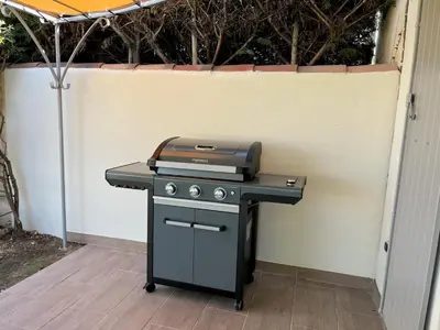 a grill sitting on a table next to a wall at Golf de Pont Royal Villa des Alpilles climatisée 3 chambres Piscine chauffée Parking et Garage in Mallemort