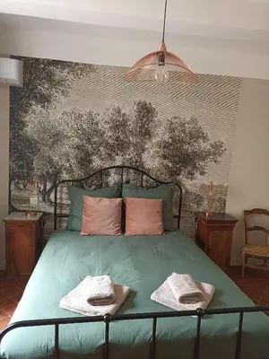 a bedroom with a green bed with two towels on it at Maison Rosiris in Pernes-les-Fontaines
