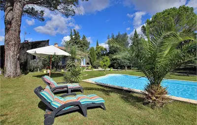 two lounge chairs and an umbrella next to a swimming pool at Lovely Home In Cheval-Blanc in Cheval-Blanc