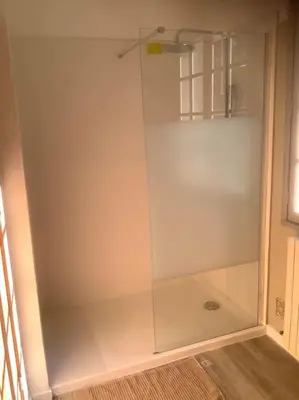 a glass shower door in a room with a floor at Le chant de la sorgue in LʼIsle-sur-la-Sorgue