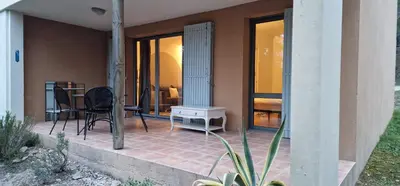 a house with a patio with a table and chairs at Appartement climatisé sur golf de L'Isle-Sur-La-Sorgue in Saumane-de-Vaucluse