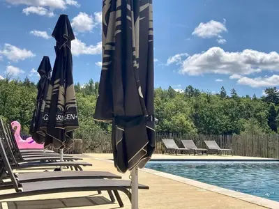 a group of chairs with umbrellas next to a pool at La Grisonne - Gîte Nordine in Revest-du-Bion