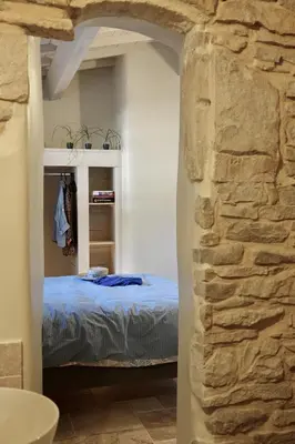 a bedroom with a bed and a stone wall at La Grisonne - Gîte Nordine in Revest-du-Bion