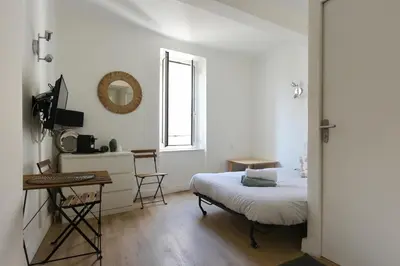a bedroom with a bed and a desk and a window at Studio Garrigue in La Fare-les-Oliviers