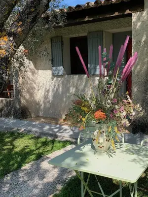 a table with a vase of flowers on it at Gîte La loge 142 route de CARPENTRAS 84210 VENASQUE in Venasque