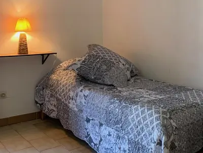 a bed in a room with a lamp on a table at Gîte La loge 142 route de CARPENTRAS 84210 VENASQUE in Venasque