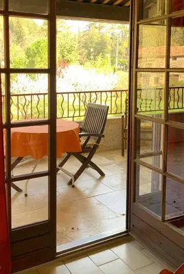 a room with a table and a chair on a balcony at Gîte La loge 142 route de CARPENTRAS 84210 VENASQUE in Venasque