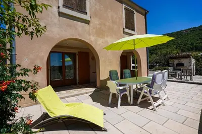 a patio with a table and chairs and an umbrella at Mon Ventoux - Cozyhotes in Sault-de-Vaucluse