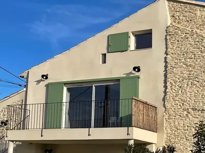 a building with green doors and a balcony at Clos du Cardinal avec piscine in LʼIsle-sur-la-Sorgue