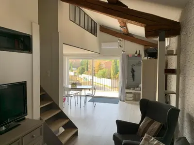 a living room with a television and a table with chairs at Clos du Cardinal avec piscine in LʼIsle-sur-la-Sorgue
