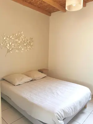 a bedroom with a bed with white sheets at Charmant T2 avec extérieur au cœur du Vaucluse in Châteauneuf-de-Gadagne