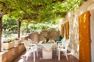 a patio with a table and chairs under a pergola at Gîte St Roch en Luberon in Castellet