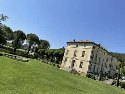 a large building on a grassy hill with trees at Chateau Talaud in Loriol-du-Comtat