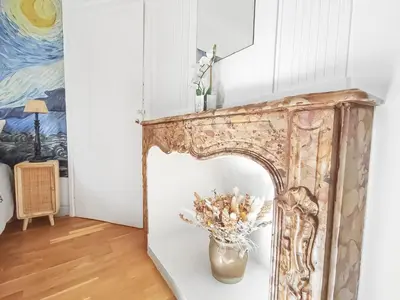 a fireplace in a living room with a vase of flowers at L'Isle d'Or - La Nuit Etoilée in LʼIsle-sur-la-Sorgue