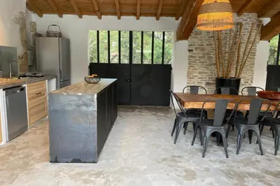 a kitchen with a table and chairs and a black door at Mas Sylvie - Isle-sur-la-Sorgue in LʼIsle-sur-la-Sorgue