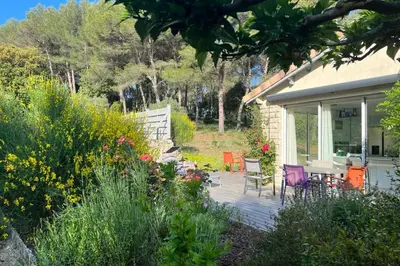 a house with a deck with chairs and flowers at Beautiful house in the heart of its pine forest - private pool in Les Taillades
