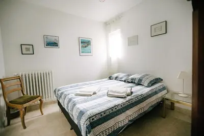 a white bedroom with a bed and a chair at Beautiful house in the heart of its pine forest - private pool in Les Taillades