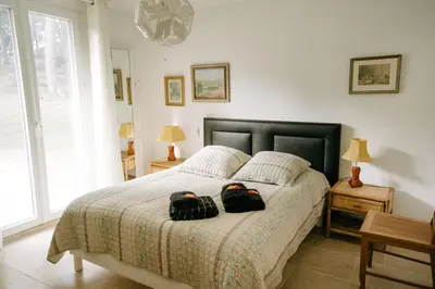 a bedroom with a bed with two bags on it at Beautiful house in the heart of its pine forest - private pool in Les Taillades