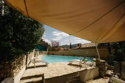 a swimming pool with chairs and a large umbrella at Villa Balleti - private pool with a view in Apt