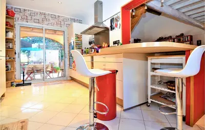 a kitchen with a red counter and white stools at Gorgeous Home In Eyragues in Eyragues