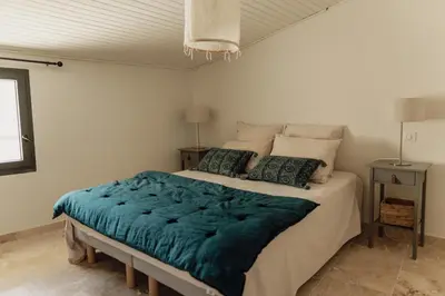 a bedroom with a large bed with a blue blanket at L'Olivier in Mormoiron