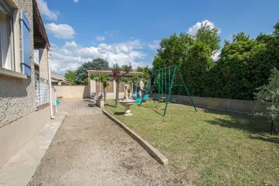 a playground in a yard with a swing at La Villa des Sorgues in LʼIsle-sur-la-Sorgue
