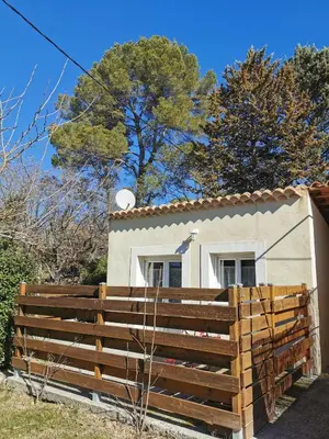 a house with a wooden fence in front of it at Studio indépendant à 2 minutes du golf du Luberon in Pierrevert