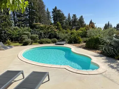 a swimming pool in a yard with two chairs around it at Beau studio en duo au coeur du Luberon in Saumane-de-Vaucluse