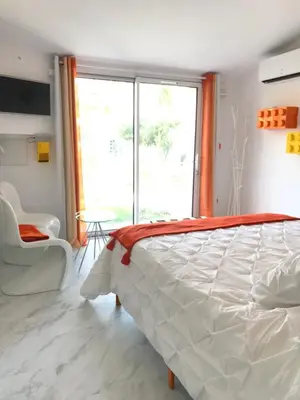 a bedroom with a white bed and a large window at La Maison 1440 in LʼIsle-sur-la-Sorgue