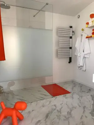 a glass shower in a bathroom with a red chair at La Maison 1440 in LʼIsle-sur-la-Sorgue