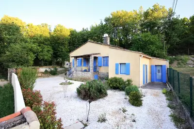 a small house with blue doors in a yard at La Cerisaie, maison spacieuse en Lubéron in Saint-Martin-de-Castillon