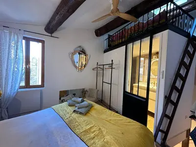 a bedroom with a large bed and a staircase at Duplex Atelier / coeur de Lourmarin in Lourmarin