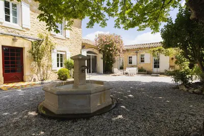 a large stone fountain in front of a building at Chambre d'hôtes - B&B - Fleur de coton chez Manon en Luberon in Lagnes