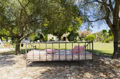 a bed sitting under a tree in a yard at Chambre d'hôtes - B&B - Fleur de coton chez Manon en Luberon in Lagnes