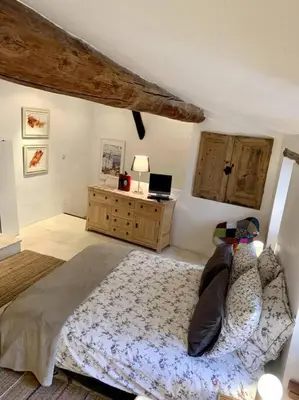 a bedroom with a bed and a desk with a laptop at La Petite Cave in Saignon