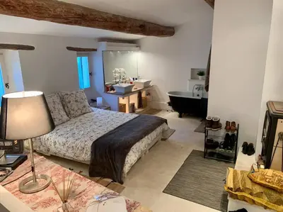 a bedroom with a bed and a bathroom with a tub at La Petite Cave in Saignon