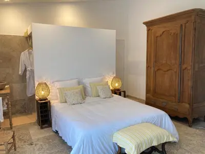 a bedroom with a large white bed and a wooden cabinet at Chambre d'hôtes de la cime in Cabrières-dʼAigues