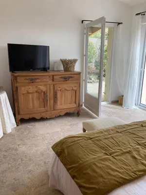 a bedroom with a television on a wooden dresser at Chambre d'hôtes de la cime in Cabrières-dʼAigues