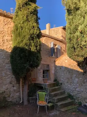a green chair sitting next to a stone building with stairs at Maison de caractère au coeur de la Provence in Robion en Luberon