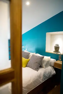 a bedroom with a blue wall and a bed with pillows at AJOUCADOU le nid in Lourmarin