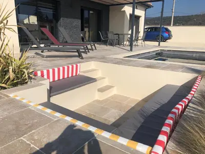 a bench sitting on a patio next to a pool at La Petite Reine in Villes-sur-Auzon