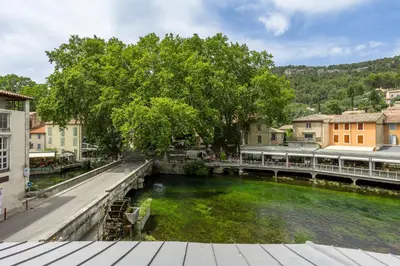 a bridge over a river in a town at Le Château Olive et Raisin in Fontaine-de-Vaucluse