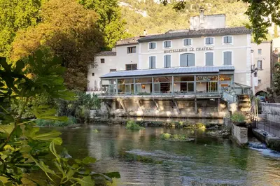 a building on the side of a river at Le Château Olive et Raisin in Fontaine-de-Vaucluse