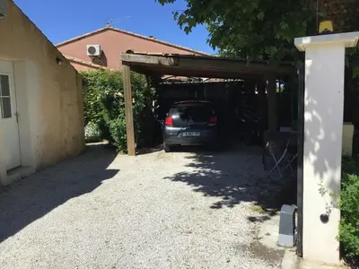 a car is parked under a wooden garage at UNE CHAMBRE EN VILLE in LʼIsle-sur-la-Sorgue