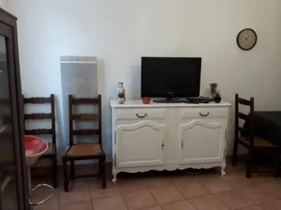 a living room with a tv on a cabinet with chairs at Apt en Luberon appartement 3 chambres et garage privée in Apt