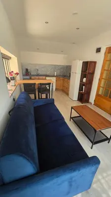 a blue couch in a living room with a kitchen at Le nid’Ange in Velleron