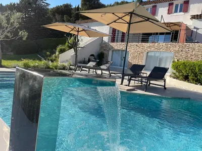 a fountain in a pool with chairs and umbrellas at The View Aix-en-Provence in Aix-en-Provence